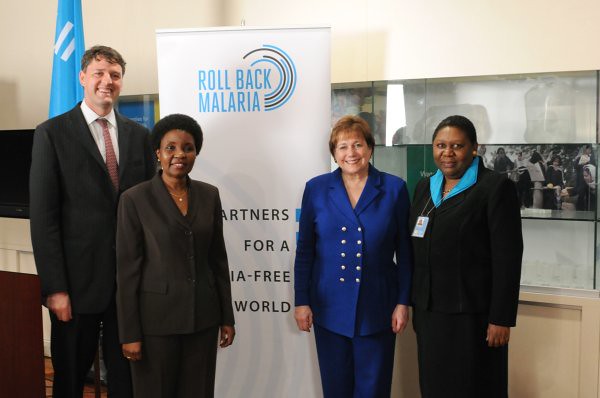 Four leaders posing in front of a Roll Back Malaria Banner.