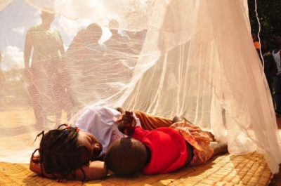 Mulher com uma criança sob uma rede mosquiteira